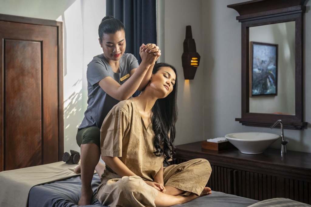 A therapist giving a shoulder and neck massage to a relaxed woman in the serene Amret Spa at The Aviary Hotel Siem Reap